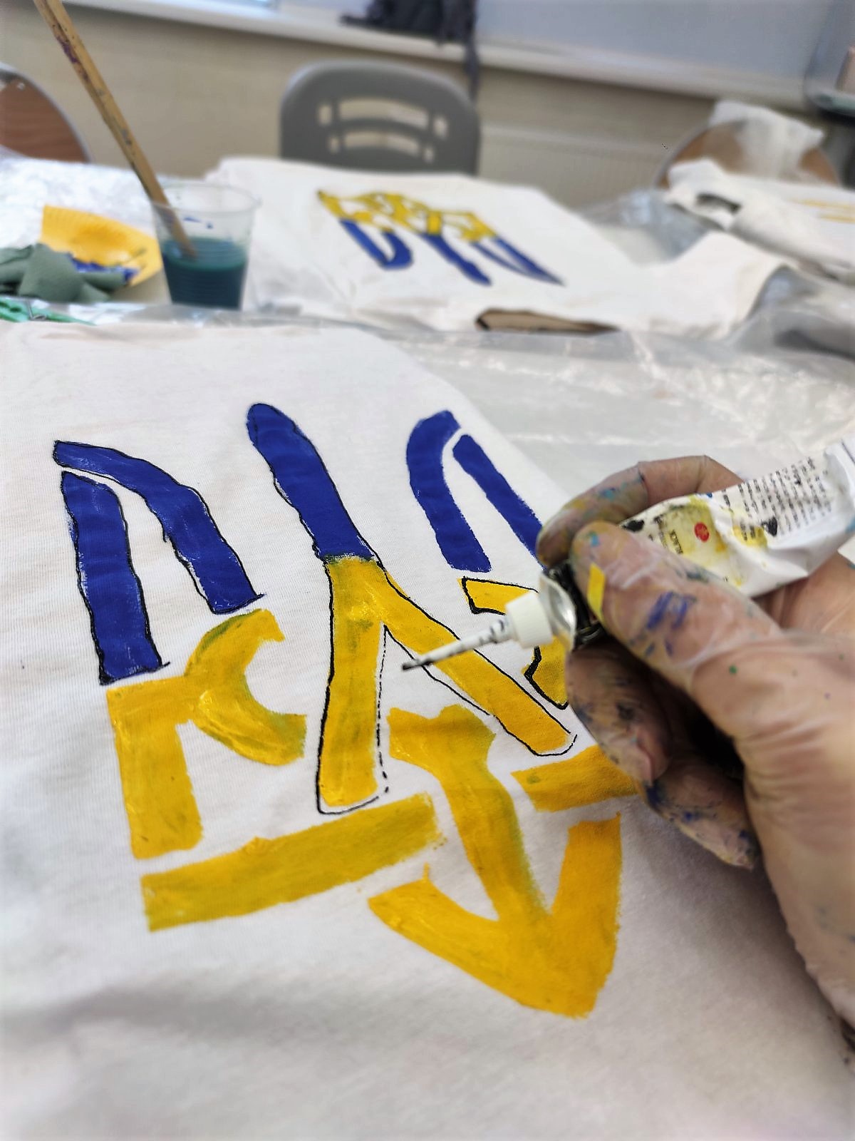 Дитина розписує патріотичну футболку жовто-блакитними фарбами на майстер-класі від «Творчої Мозаїки».