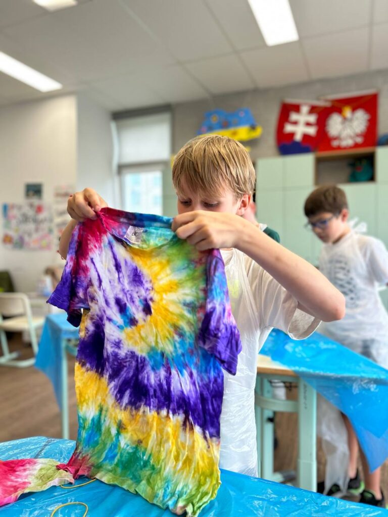 Хлопчик тримає футболку, розписану у техніці Тай Дай на дитячому майстер-класі від Творчої Мозаїки