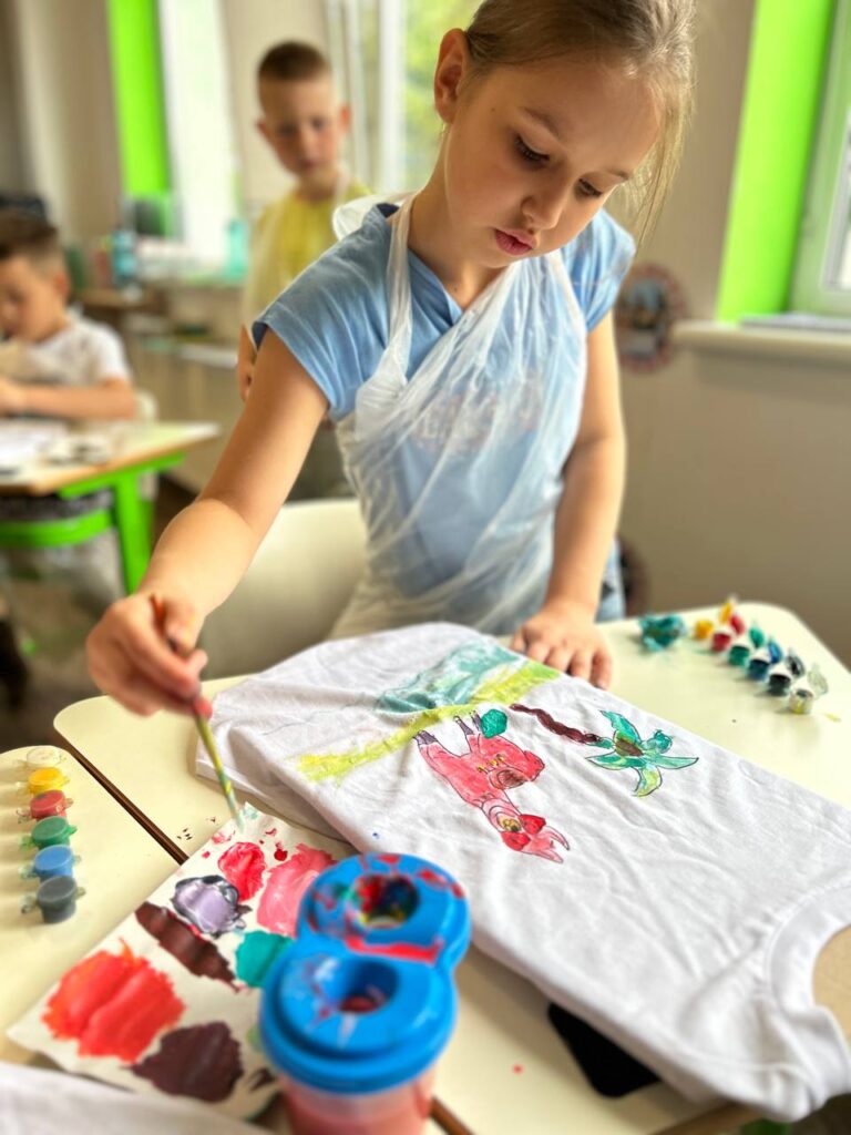 Дитина розписує футболку акриловими фарбами на майстер-класі з розпису футболок від «Творчої Мозаїки».