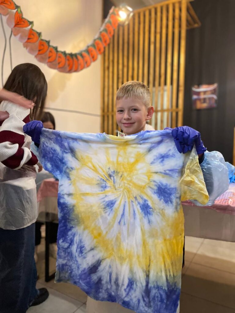 Дитина тримає жовто-блакитну футболку Тай Дай після майстер-класу Творчої Мозаїки