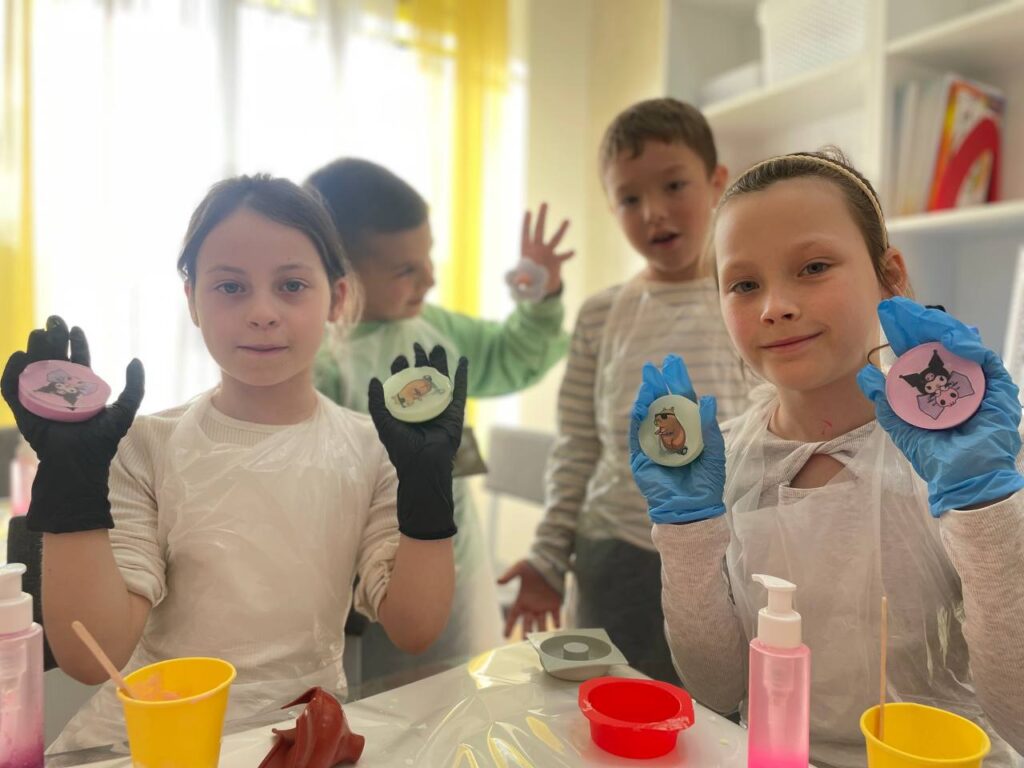 Дві дівчинки тримають різнокольорове мило, зроблене на дитячому майстер-класі з миловаріння