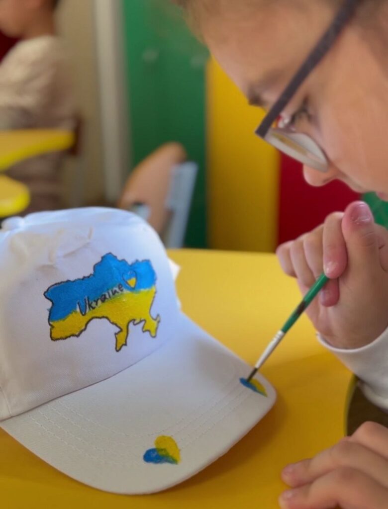 Дитина малює контур України на кепці