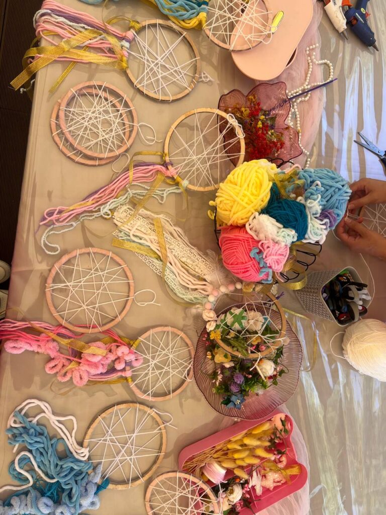 Стіл із готовими ловцями снів, створеними на майстер-класі в Києві — різнокольорові обереги з намистинами, пір’ям і мереживом.