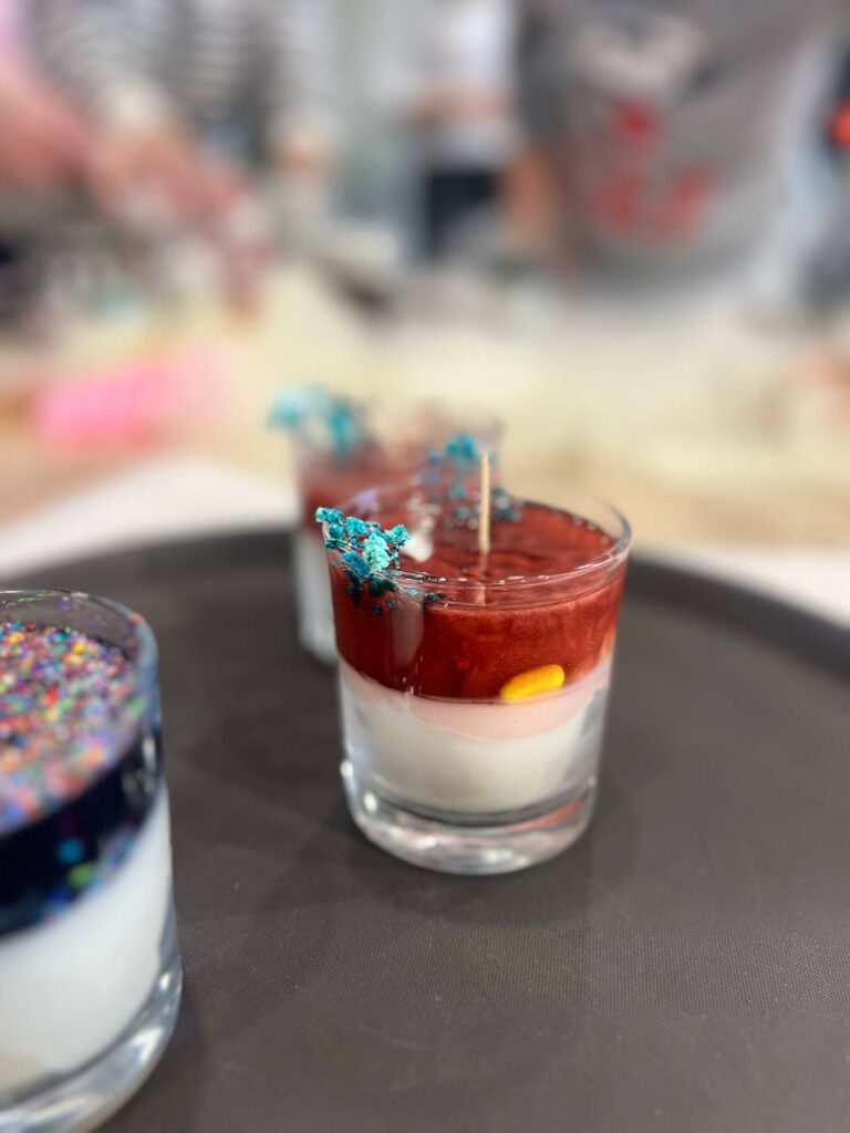 Крупний план ароматних свічок у банках із різними наповненнями: мушлі, камінці, сушені квіти.