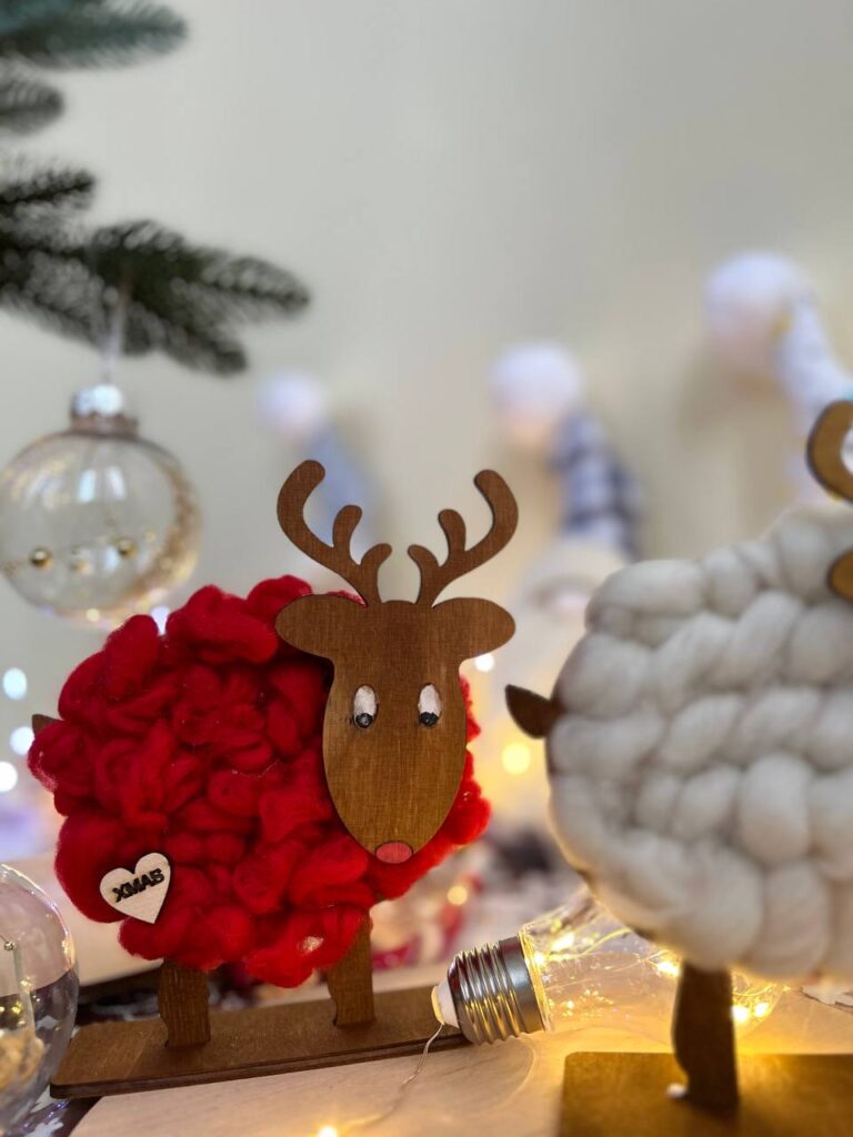 Учасниця прикрашає оленя помпонами та зірочками під час майстер-класу «Олені з вовни».