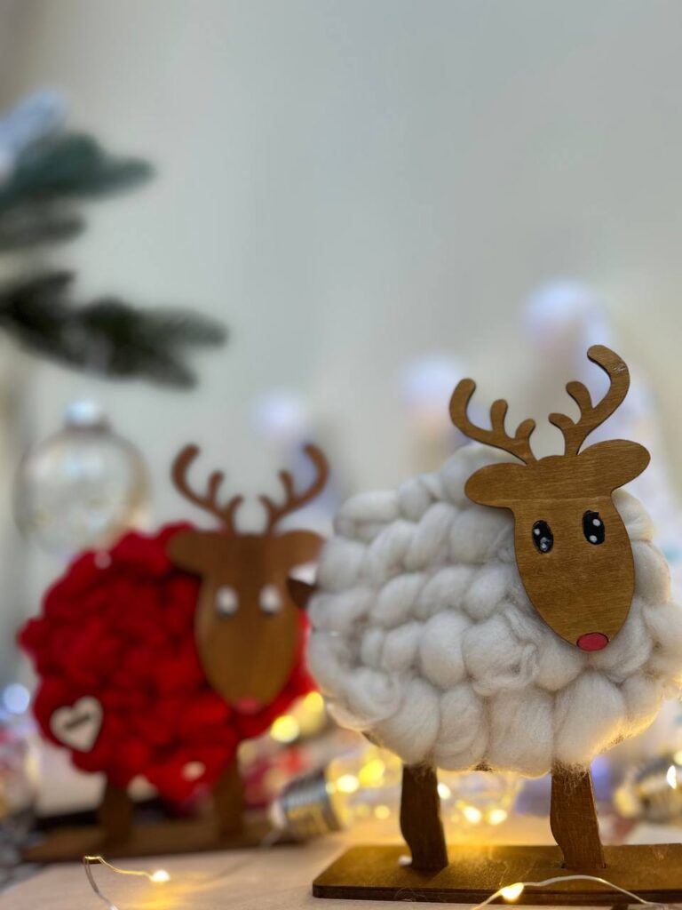 Учасниця прикрашає оленя помпонами та зірочками під час майстер-класу «Олені з вовни».