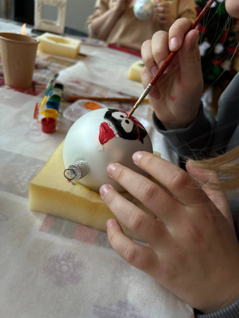Учасники тримають власноруч розписані новорічні кульки після святкового майстер-класу «Творчої Мозаїки».