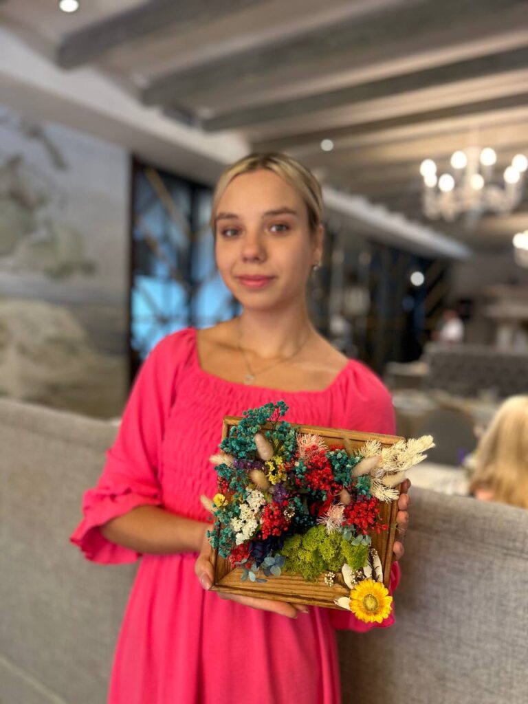 Учасниця підбирає сухоцвіти для створення квіткової композиції під час творчого майстер-класу.