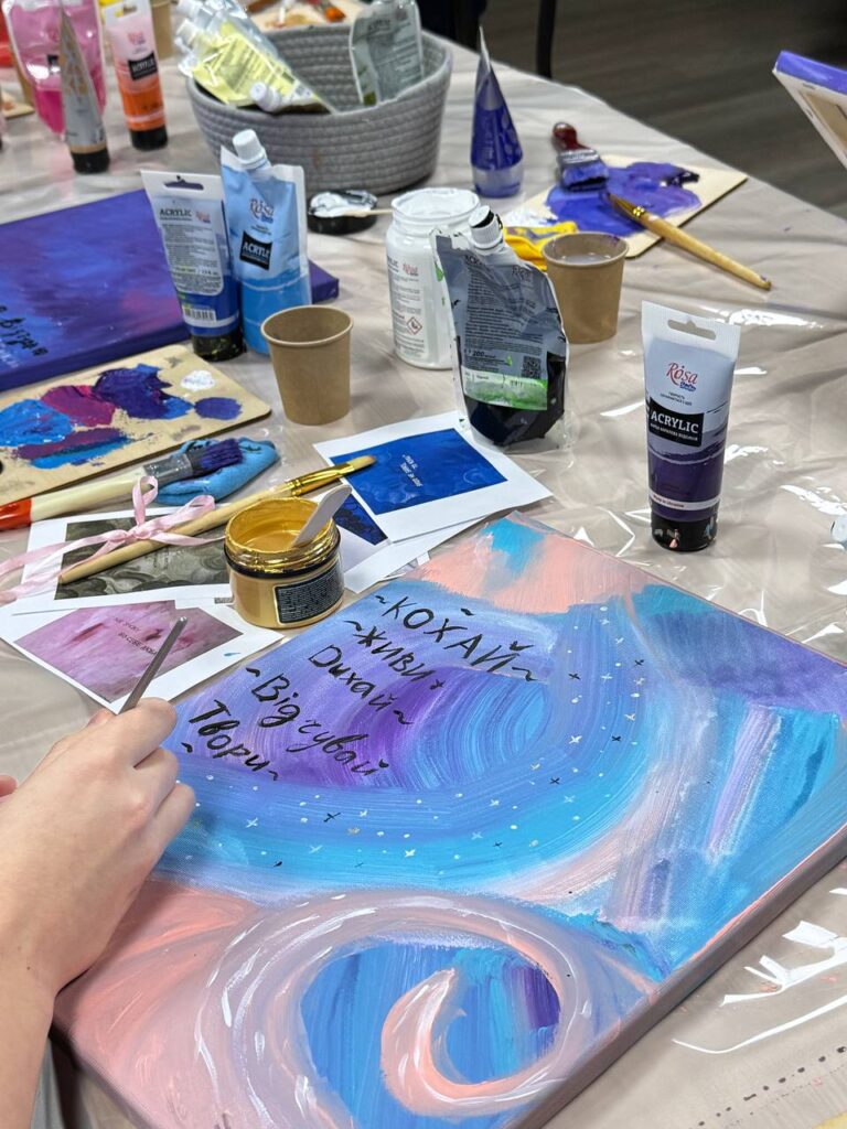 Процес створення картини з афірмацією: нанесення фону та надпису на полотно.