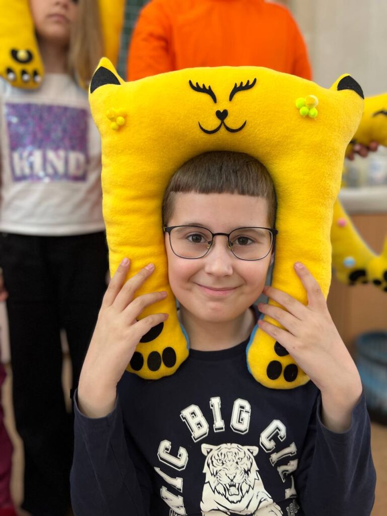 Хлопчик приміряє м’яку тревел подушку-котика, створену власноруч на дитячому майстер-класі.