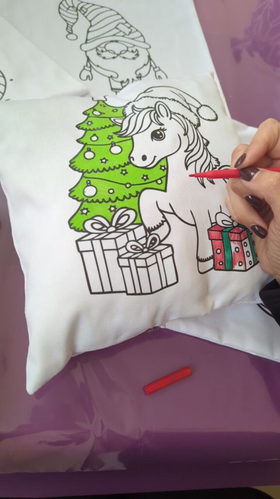 Процес розпису подушки з поні та подарунками під час новорічного майстер-класу для дітей.